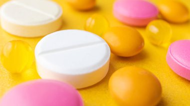 Sarı arka planda çok renkli haplar. Pankart 16: 9. Virüslere, ilaçlara, hastalıkların önlenmesine ve tedavisine karşı koruma kavramı. Makro, minimalizm. 