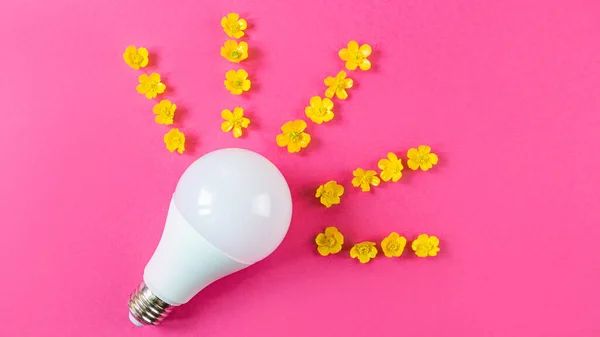 Светодиодная Лампа Лежит Ярко Розовом Фоне Поблизости Желтые Цветы Лежат — стоковое фото