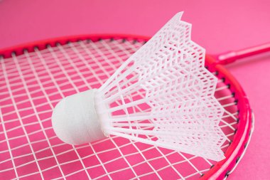 Badminton raketi ve parlak pembe bir arka planda mekik penisi. Amatör sporların envanter konsepti. Minimalizm.