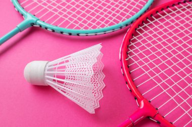 Badminton raketleri ve parlak pembe bir arka planda mekik penisi. Amatör sporlar için ekipman kavramı. Minimalizm.