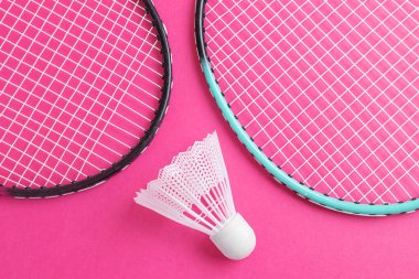 Badminton raketleri ve parlak pembe bir arka planda mekik penisi. Amatör sporlar için ekipman kavramı. Minimalizm.