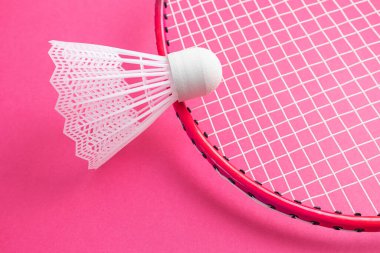 Badminton raketi ve parlak pembe bir arka planda mekik penisi. Amatör sporların envanter konsepti. Minimalizm.