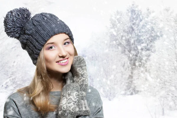 Retrato de invierno de una joven sonriente con un sombrero de punto. Sombrero de invierno y guantes de punto. alegre chica nevado fondo — Foto de Stock