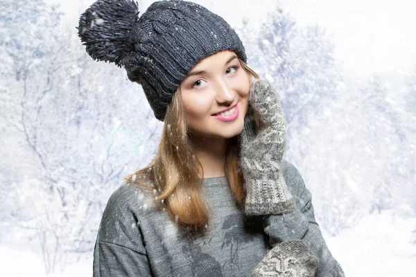 Зимний портрет молодой улыбающейся женщины в вязаной шляпе. Зимняя шляпа и вязаные варежки. веселая девушка на снежном фоне — стоковое фото