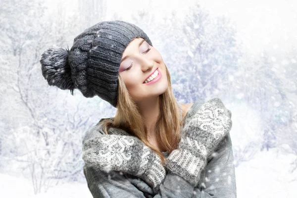 Ritratto invernale di una giovane donna sorridente con un cappello a maglia. Cappello invernale e guanti lavorati a maglia. allegra ragazza sfondo nevoso — Foto Stock