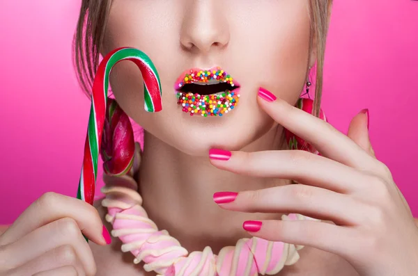 Close-up of the female face. Open mouth. Lips sprinkled with colored jelly beans. Accessories made of sweets. Food. Concept — Stock Photo, Image