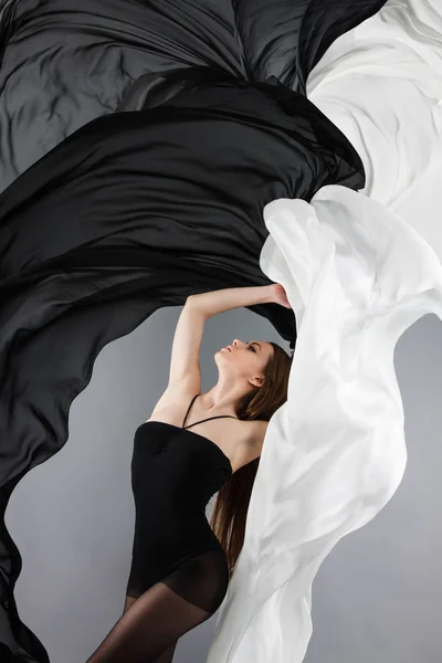 Schöne junge Mädchen tanzen. schwarzer und weißer Stoff in Bewegung. Fliegender Stoff — Stockfoto