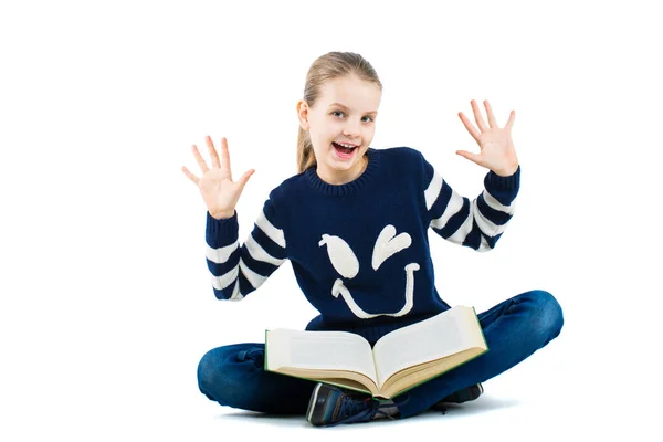 Glad tjej med upphöjda händer. Flicka sitter på golvet med en stor bok — Stockfoto