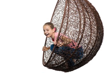 The girl rests in a hanging chair made of rattan. clipart
