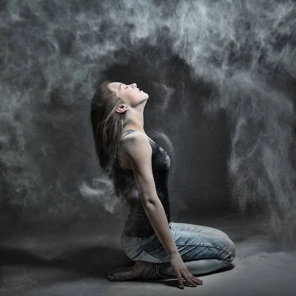 Zarif kadın toz bulutu içinde dans. Kız un, gri arka planda