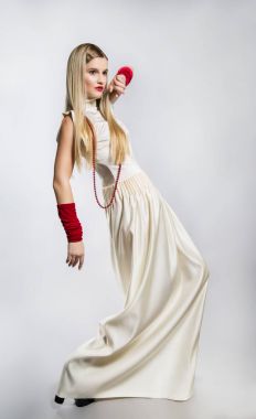 Stüdyoda uzun beyaz elbiseli bir kız modeli. uzun sarı saçlı, kırmızı eldiven
