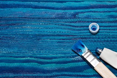 güzel ahşap arka plan parlak mavi boya ile boyanmış. bir tüp boya ve fırça açın