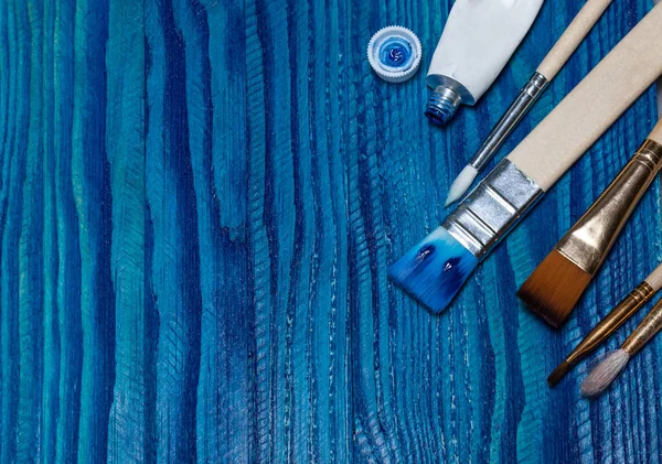 güzel ahşap arka plan parlak mavi boya ile boyanmış. bir tüp boya ve fırça açın
