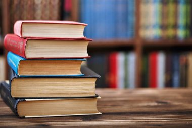 ahşap bir masa üzerinde eski kağıt kitap yığını. Raflardan içinde belgili tanımlık geçmiş. Arka plan bulanık