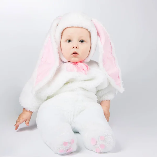 Little cute baby in a white Bunny suit. The child sits on the floor. — Stock Photo, Image