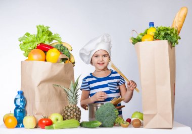 Şef şapkalı çuval dolusu yiyecek ile mutlu küçük kız. A