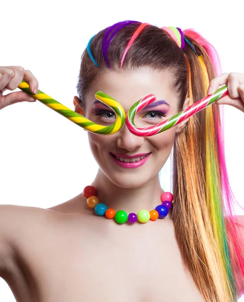 Porträt eines jungen Mädchens mit farbenfrohem, kreativem Make-up und farbigen Haarsträhnen. die Frau hält farbige Bonbons in den Händen. — Stockfoto