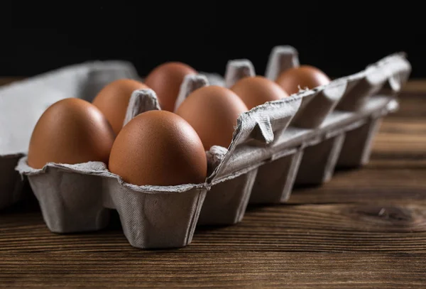 Bir kutu içinde çiğ tavuk yumurtası close-up. Eski bir ahşap masa üzerinde yumurta