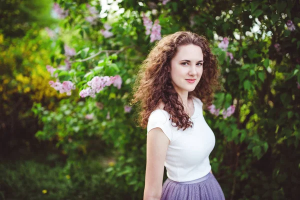 Joyeux jeune femme dans un t-shirt blanc sous les arbres en fleurs . — Photo