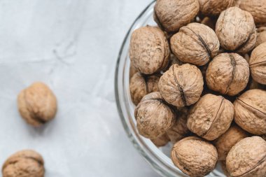 Walnuts in shell in bowl on gray background