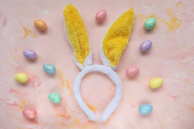 Easter eggs and rabbit ears on pink background