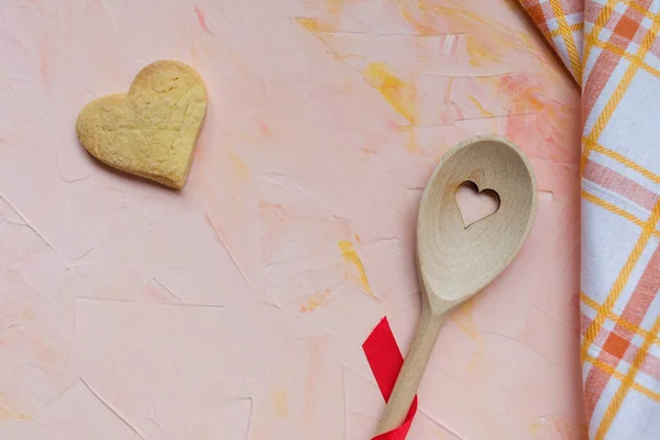 Colher agitadora e biscoito de manteiga em forma de coração em um fundo rosa — Fotografia de Stock