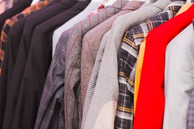 Erkek giyim mağazaları. Erkek giysisi mağazadaki bir askıya ağır basıyor. 2020 'de bir adamı nasıl giydireceğini. Kareli, siyah ve farklı renkte ceketler ve takımlar.