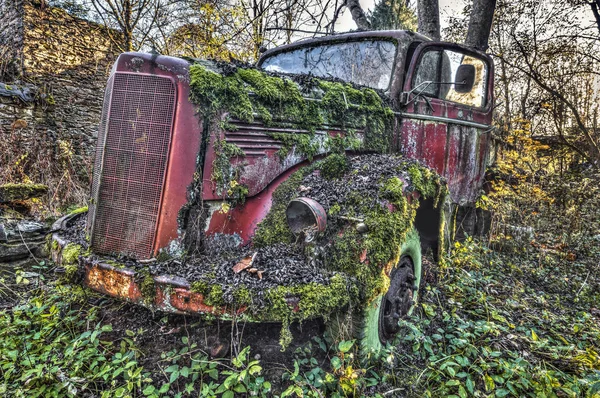 Viejo camión rojo abandonado cubierto de musgo y malezas —  Fotos de Stock