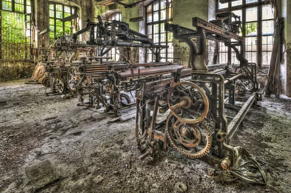 Alte Webstühle und Spinnmaschinen in einer verlassenen Fabrik Stockfoto