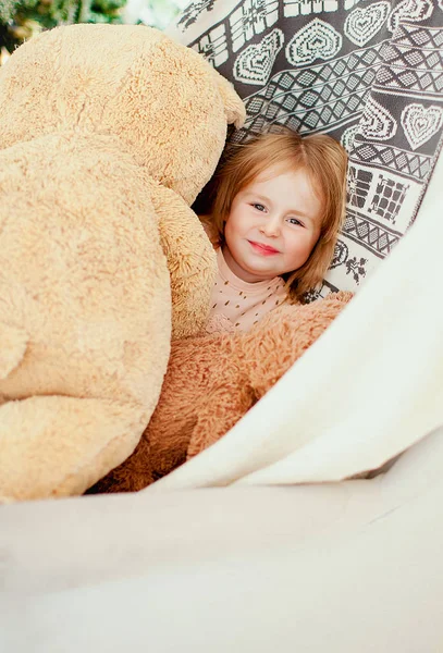 Little girl smiling and surrounded by teddy bears. — Stock Photo, Image