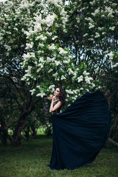 Beautiful young girl in a flowering lilac. — Stock Photo, Image