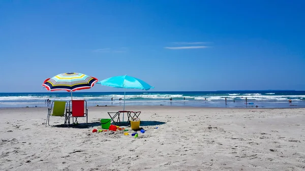 Sun umbrellas at the beach with children's toys on a sunny day — Stock Photo, Image