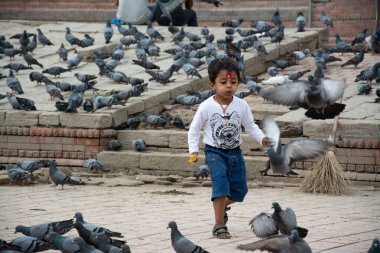 Katmandu, Nepal - 10 Mayıs 2017: Küçük bir çocuk Pashupatinath tapınağındaki bir avluda güvercinlerle oynuyor.