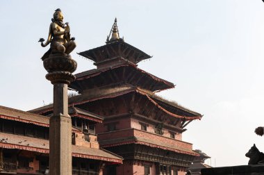 Krishna Mandir 'in ön planında, Katmandu, Nepal' deki Patan Durbar Meydanı 'nda, taş bir sütunun üzerindeki güzel Garuda heykeli..