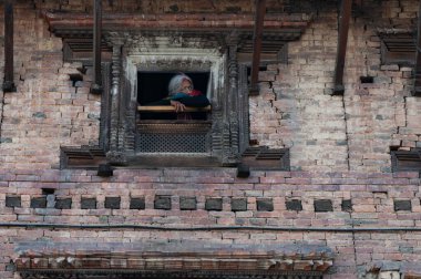 Katmandu, Nepal - 16 Ocak 2016: Kirtipur 'daki klasik evinin penceresinden dışarı bakan yaşlı bir kadın.