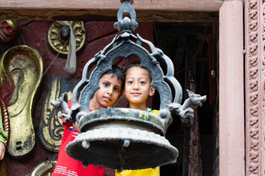 Katmandu, Nepal - 2 Eylül 2017: Buda tapınağındaki asılan lambaya bakan iki çocuk.