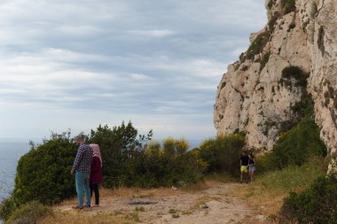 Chekka, Lübnan - 19 Mayıs 2017: Gündelik giyimli çiftler uçurumun kenarından deniz manzarasının keyfini çıkarıyorlar.