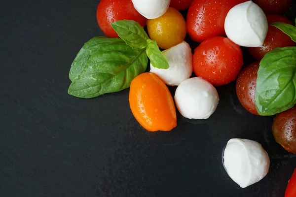 Siyah arka plan üzerine Mozzarella peyniri ile küçük taze domates