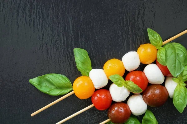 Siyah arka plan üzerine Mozzarella peyniri ile küçük taze domates