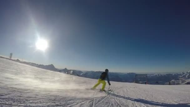 Esquiador en nieve suave en un día soleado contra el cielo despejado — Vídeos de Stock