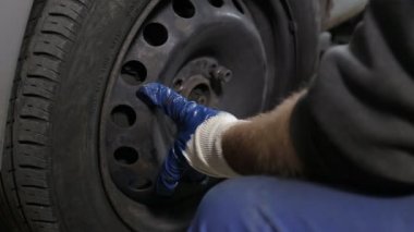 Otomobil tamircisi tekerlek lastiği değiştirmek için unscrews