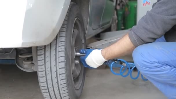 Автомеханик прикручивает колесо к машине — стоковое видео