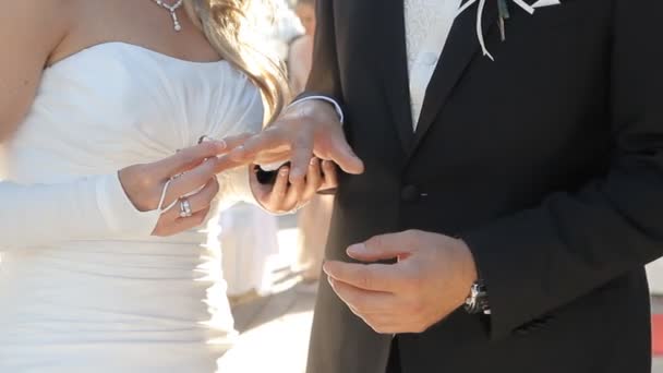 Невеста надевает обручальное кольцо на палец жениха — стоковое видео