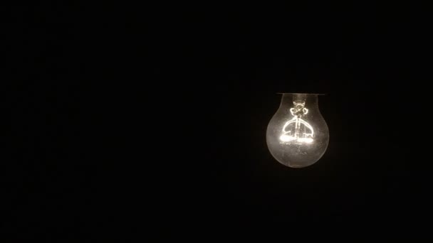 Glowing hanging light bulb dangle on a wire loop 4K — Stock Video