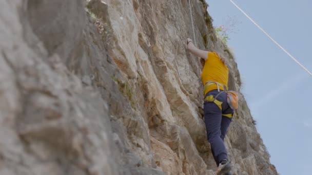 Uma alpinista do sexo feminino sobe uma rocha — Vídeo de Stock