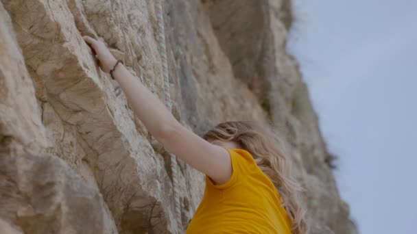 Een vrouwelijke rock klimmer klimt op een rots — Stockvideo