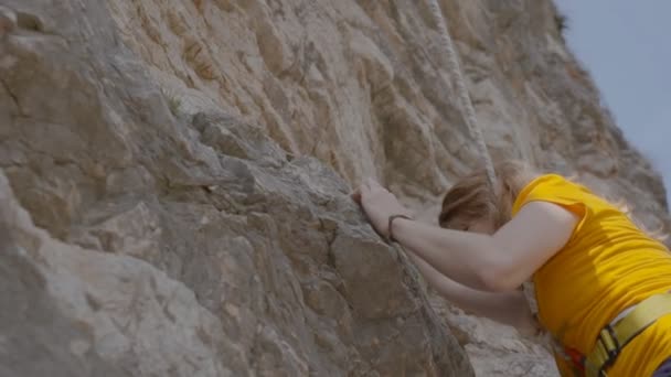 Een vrouwelijke rock klimmer klimt op een rots — Stockvideo