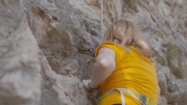 Una escaladora trepa por una roca — Vídeo de stock