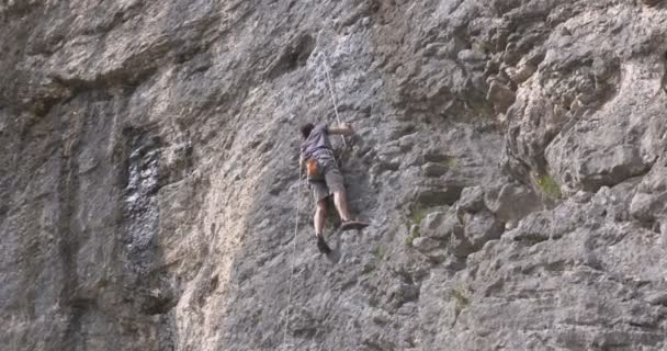 A male rock climber climbs up a rock — Stock Video