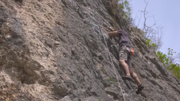 A male rock climber climbs up a rock — Stock Video